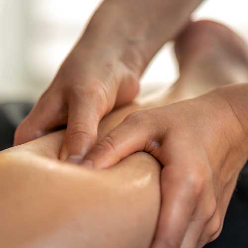 A massage therapist’s hands working on a client’s leg